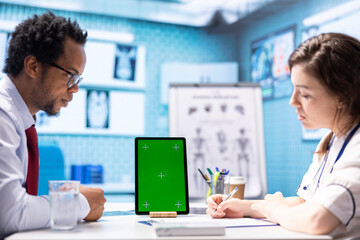 Doctor meeting with a patient in medical office next to copy space on display, employing medical technology at the hospital. Specialist physician helping a man with disease at check up.