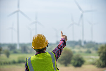 A thumbs-up for green energy:  A construction worker in a yellow hard hat and safety vest gives a...