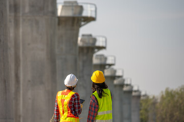 Construction Project Oversight: Two construction workers wearing hard hats and safety vests engage...