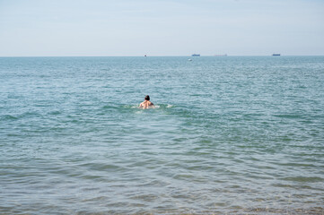 A man swims in the sea. View of the back.