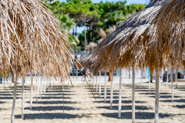 Beach with straw umbrellas close up. Shadows on the sand.