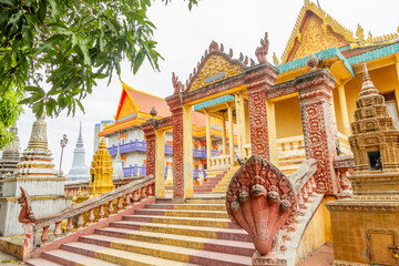 Fototapeta premium Colorful yellow buddist Monkey temple surrounded by stupas and Naga statues, Phnom Penη, Cambodia