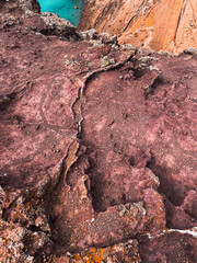 Madeira island Portugal no people red clay close up texture stones sand relaxation hiking trail aerial view cliff hill Atlantic ocean vacation blue water vertical photography sightseeing seascape
