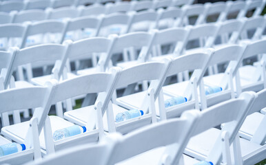 Outdoor Event Seating Rows of White Chairs with Water Bottles Chuppah seating arranged 