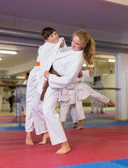 Sporty teenager children practicing new self defense moves in pairs at sport gym