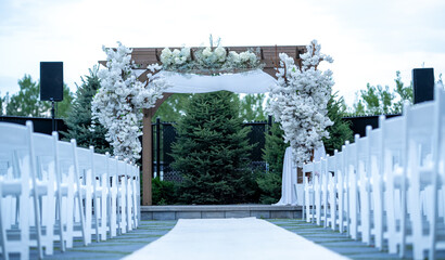Chuppah Wedding arch is decorated with cloth and flowers outdoors. Beautiful wedding set up. Wedding ceremony Part of the festive decor, floral arrangement.
