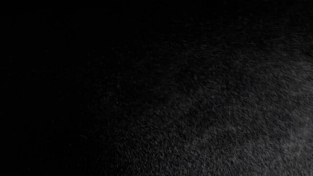 Jet of spraying water droplets, deodorant or other liquid on a black background, close up. Spray water drop or steam or fog