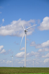 Fototapeta premium Giant white wind turbine windmill with blue sky and cumulus clouds