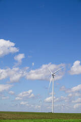 Fototapeta premium Giant white wind turbine windmill with blue sky and cumulus clouds