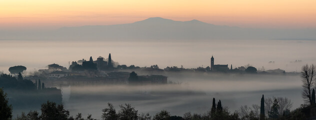 Silhouette of buildings in fog during early morning in Siena