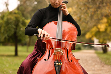 Young woman playing cello in park, closeup