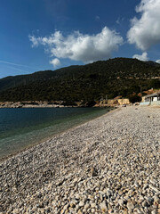 Relaxing day at a pebbled beach near a scenic mountain backdrop in clear weather