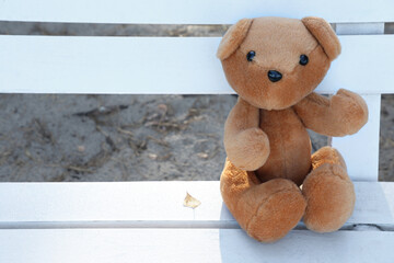 Lonely teddy bear on bench in park