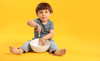 Cute little boy with bowl and whisk on yellow background. Space for text