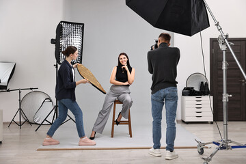 Photographer and assistant working with model in professional photo studio