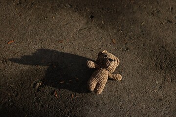 Lost knitted bear on ground outdoors, above view