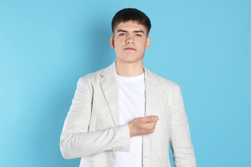 Man making promise on light blue background. Oath gesture