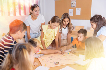 Teacher and schoolchildren play a table game in school class