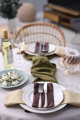 Festive table setting with dishware, cutlery, glasses, desserts and wine indoors