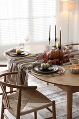 Stylish table setting with beautiful dishware and autumn decor in dining room
