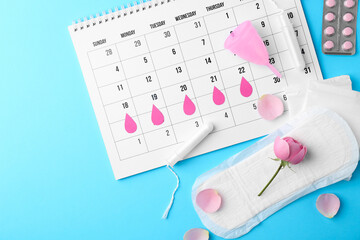 Fototapeta premium Flat lay composition with calendar and menstrual products on light blue background