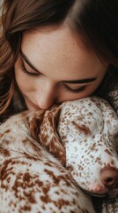 A woman is hugging a dog with white spots. The dog is sleeping. The woman is wearing a sweater