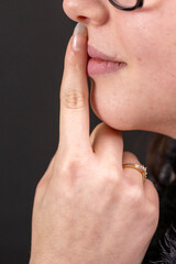 doigt sur la bouche d'une jeune faire pour faire silence sur fond noir © Esta Webster