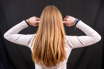 jeune femme blonde aux cheveux longs se bouchant les oreilles avec les doigts