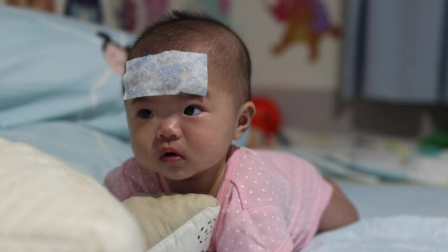 Asian Baby girl on high fever with cool fever jel pad on forehead