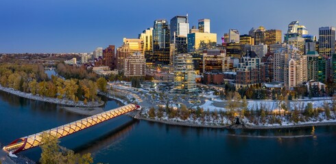 Calgary's Peace Bridge at twilight, snow-covered parkland, and illuminated city skyline. Urban landscape in winter. Downtown, Calgary, Alberta, Canada