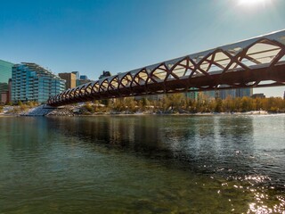 Stunning view of the Peace Bridge over the Bow River in Calgary, Alberta, on a sunny winter day. Modern architecture and nature blend beautifully.  Calgary, Alberta, Canada