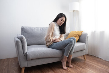 Attractive Asian young woman suffering from stomach ache, gastritis, menstruation, colitis, concept of female stomach ache.