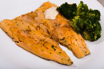 Healthy eating. Grilled fillets of trout served with boiled broccoli and creamy sauce..