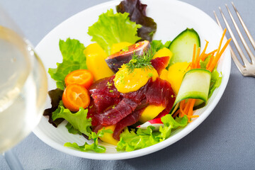 Portion of delicious salad with raw tuna fish, greens, figs and citrus