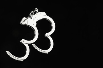 Metal chain handcuffs on black background, closeup. Space for text