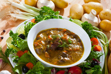 Delicious cooked goulash from chicken hearts served with vegetables and fresh lettuce at plate..