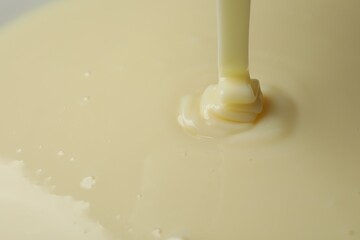Pouring delicious condensed milk as background, closeup