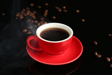 Red cup with coffee and roasted beans on black background