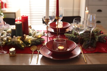 Christmas place setting with festive decor on wooden table in room