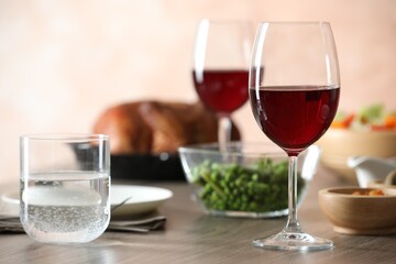 Red wine and delicious dinner served on wooden table, closeup