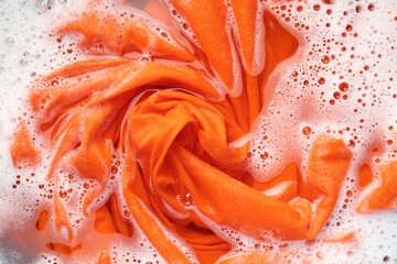 Orange clothes soaked in water before washing, top view