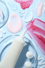 Cream, scrub and gel samples on light blue background, flat lay. Stylish presentation with tube of skincare product