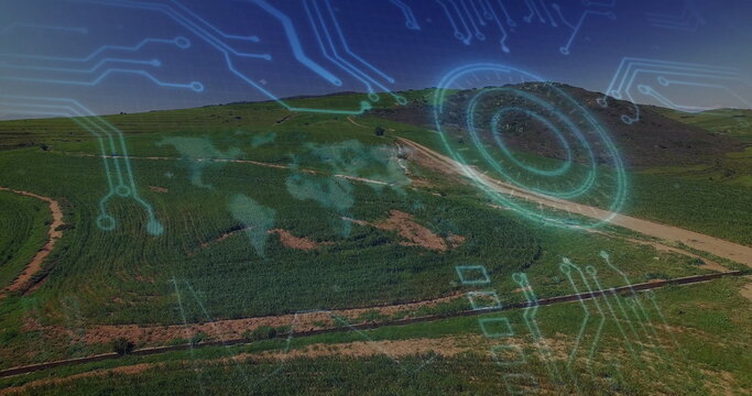 Digital circuit and world map image over aerial view of green landscape