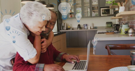 Image of lightbulb icons over senior biracial couple embracing