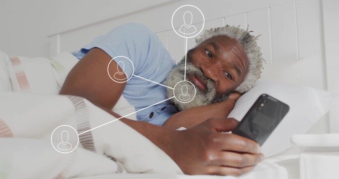 Image of network of connections with icons over senior african american man using smartphone