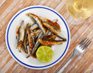 Fried anchovies with lemon on a plate closeup