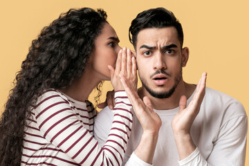 Young Arab Woman Sharing Gossips With Her Shocked Boyfriend, Whispering To His Ear, Millennial...