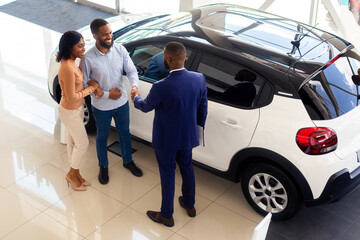 Car Dealership. Top View Shot Of Customers Couple And Black Male Manager Handshaking After...