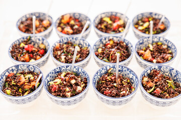 Elegant serving of Riso Venere in small round appetizer plates on a tray. This black rice dish combines gourmet style and rich flavor, perfect for sophisticated events or culinary enthusiasts.