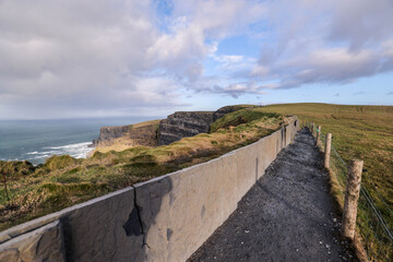 beautiful view of the path on the cliffs Ireland, unrecognizable people sitting and standing. cielo nublado, lluvia y niebla.